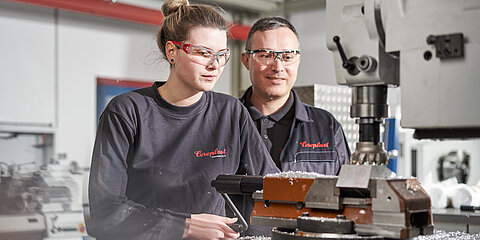 Apprentice industrial mechanic and her instructor at a machine 